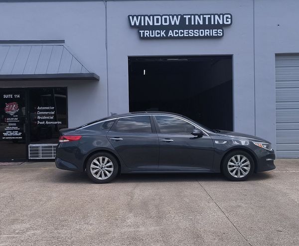 Dark gray sedan parked outside a window tinting truck accessories shop.