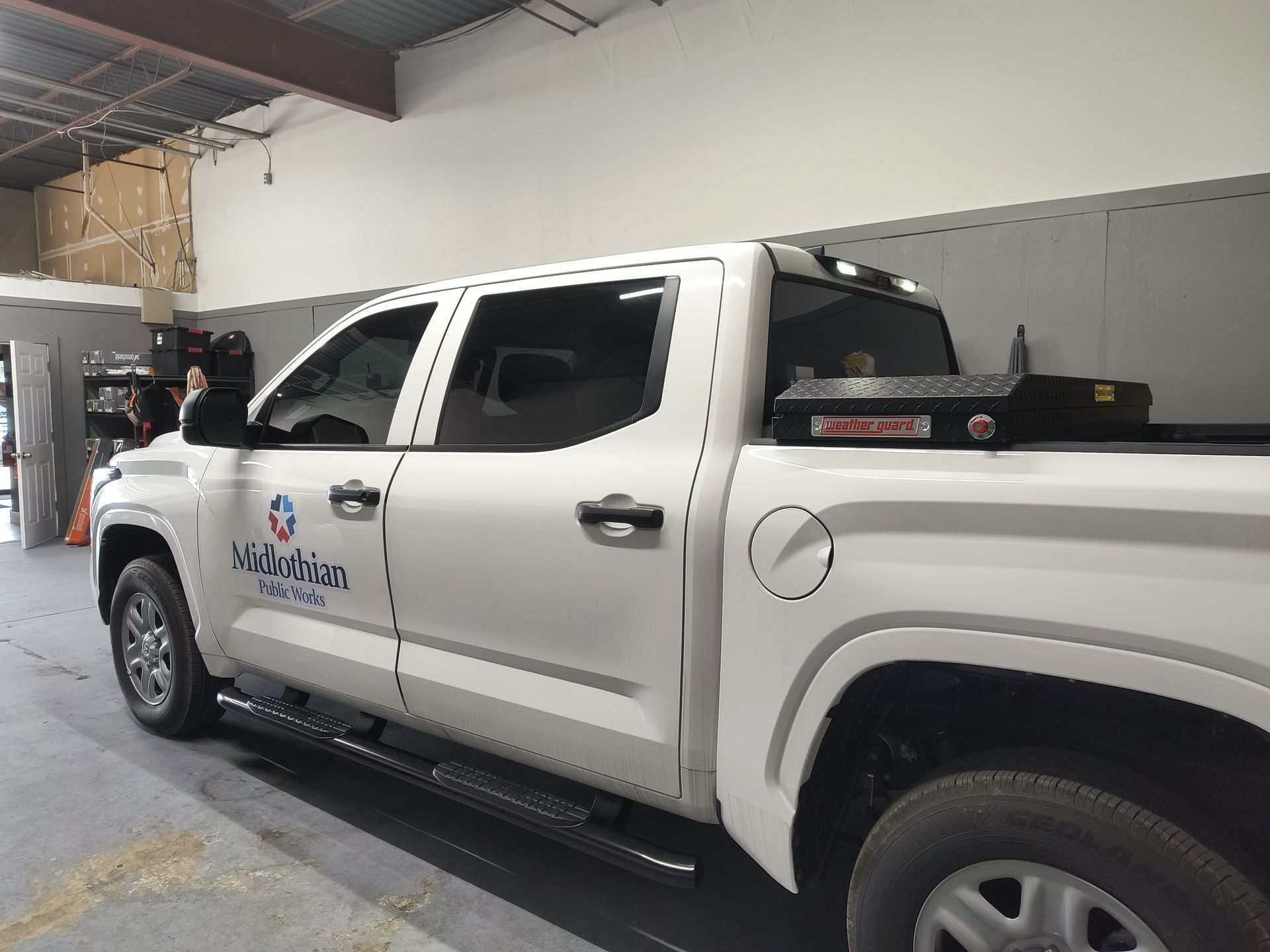 White utility pickup truck with company logo parked inside a warehouse garage