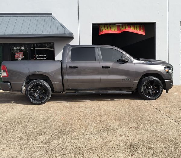 Gray pickup truck parked outside a garage with colorful lighting behind it