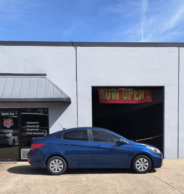 Blue sedan parked in front of a white storefront with an 