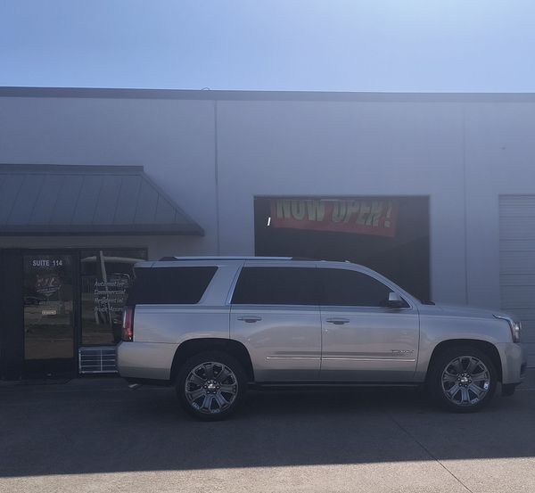 White SUV parked outside a storefront with a “Now Open” sign.