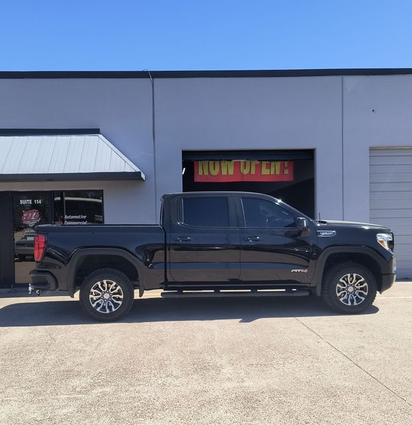 Black pickup truck parked in front of a storefront with a red “OPEN” sign
