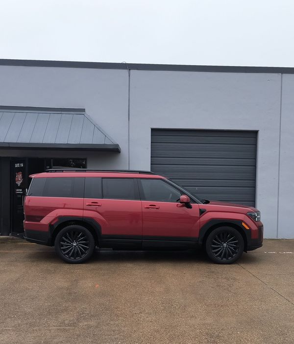 Red SUV parked beside a gray industrial building and garage door