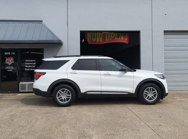 White SUV parked outside a storefront with a black-and-red sign