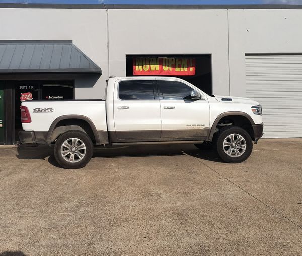 White pickup truck parked outside a building with a lit sign above the cab.