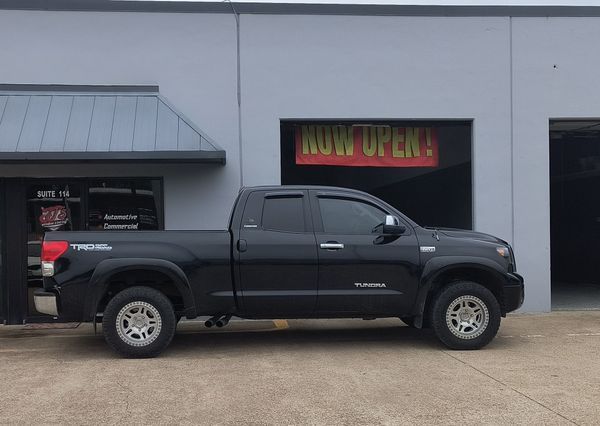 Black pickup truck parked outside a gray building with a garage door.