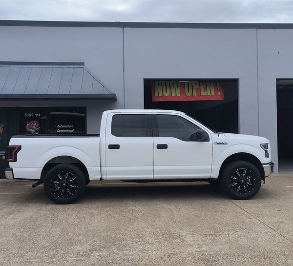 White pickup truck parked in front of a commercial building with a dark storefront sign