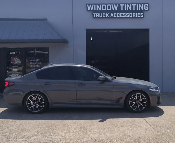 Gray sedan parked outside a window tinting and truck accessories shop