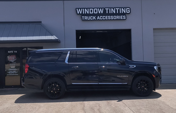 Black SUV parked in front of a window tinting truck accessories shop