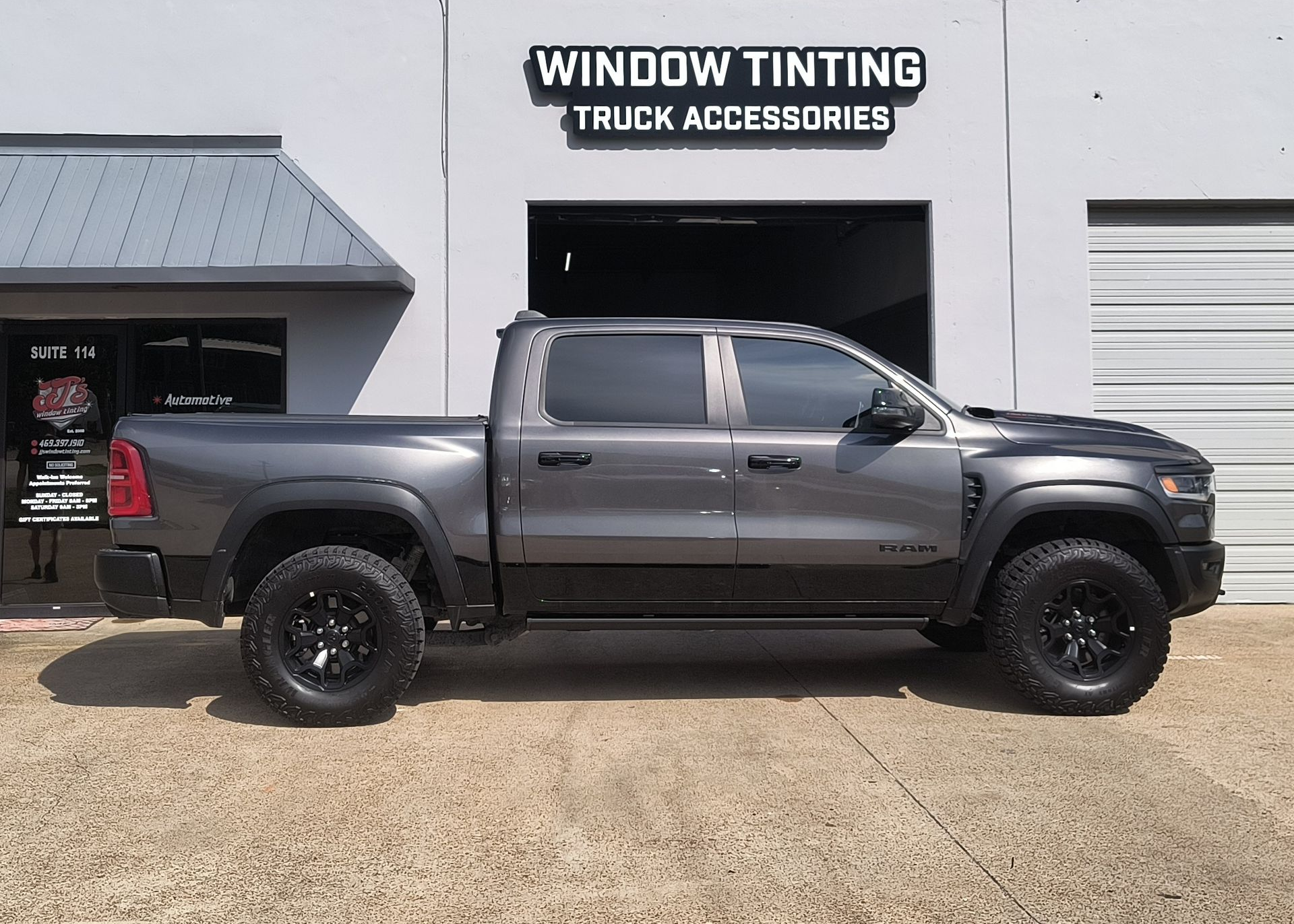 Gray pickup truck parked outside a window tinting truck accessories shop