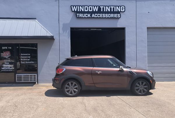 Brown Mini Cooper parked outside a window tinting and truck accessories shop