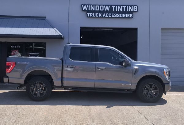 Gray pickup truck parked outside a window tinting and truck accessories shop