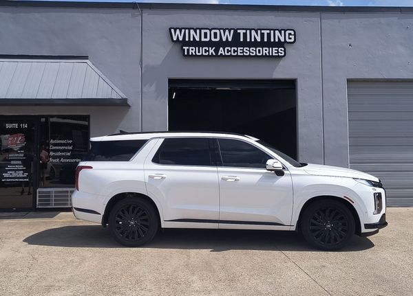 White SUV parked outside a shop labeled “Window Tinting Truck Accessories”
