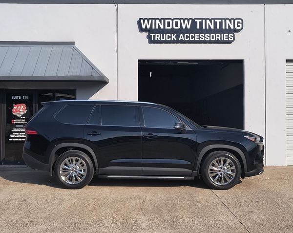 Black SUV parked outside a window tinting and truck accessories shop