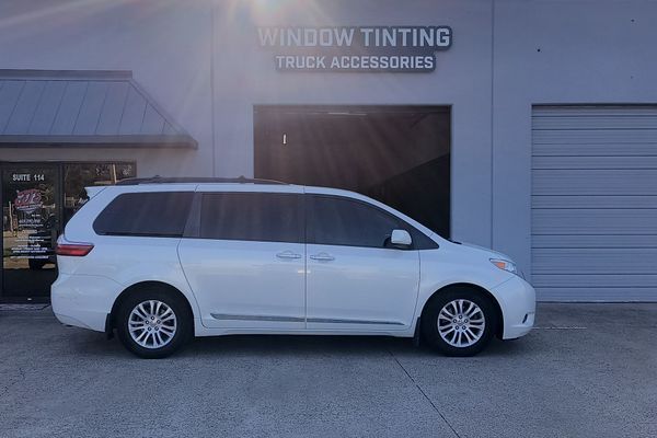 White minivan parked outside a window tinting truck accessories shop