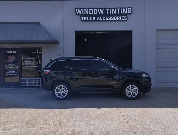 Black SUV parked outside a window tinting and truck accessories shop
