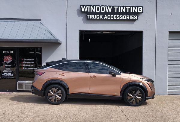 Copper-colored SUV parked outside a window tinting and truck accessories shop