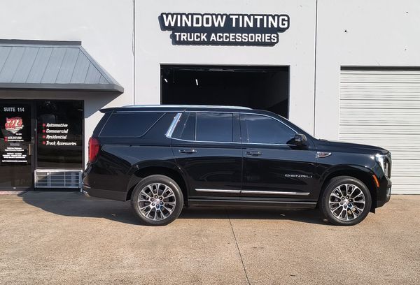 Black SUV parked outside a window tinting and truck accessories shop