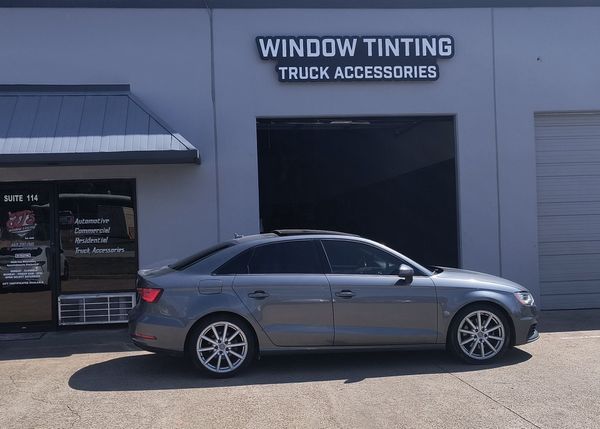 Gray sedan parked outside a window tinting truck accessories shop