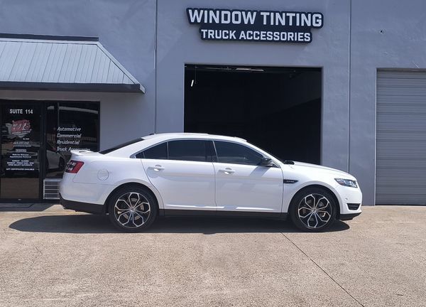 White sedan parked outside a window tinting and truck accessories shop