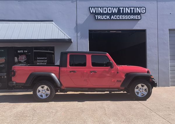 Red pickup truck parked outside a window tinting and truck accessories shop