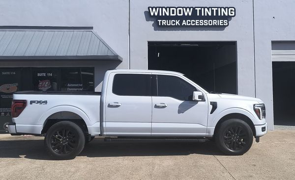 White pickup truck parked outside a window tinting and truck accessories shop