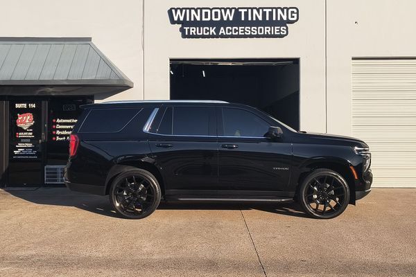 Black SUV parked outside a window tinting and truck accessories shop