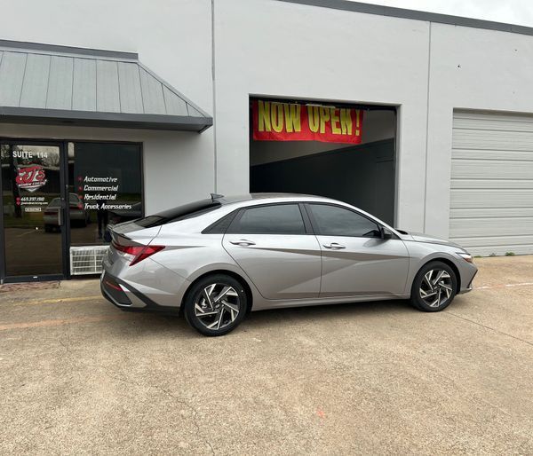 Silver sedan parked outside an auto shop with an open garage bay.