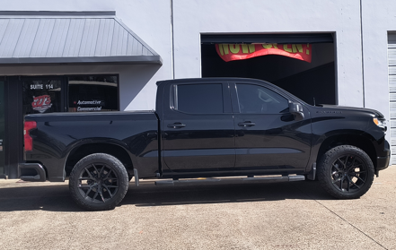 Black lifted pickup truck parked outside a building with garage doors.