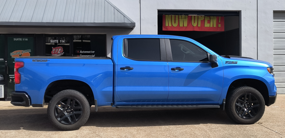 Blue pickup truck parked in front of a storefront