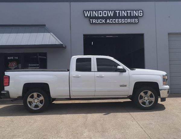 White pickup truck parked outside a truck accessories and window tinting shop