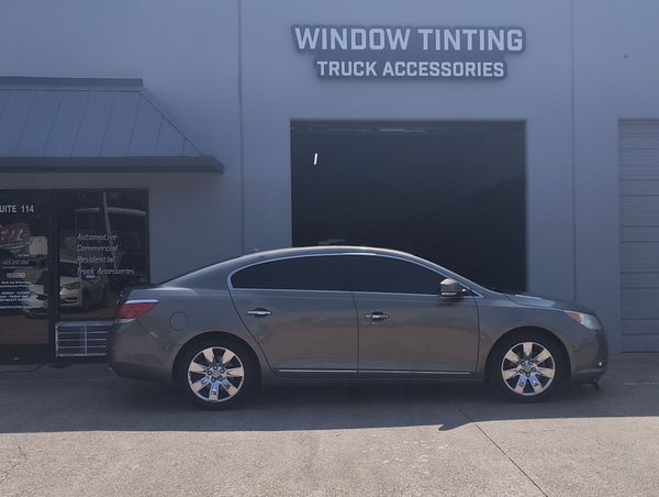 Silver sedan parked outside a window tinting truck accessories shop