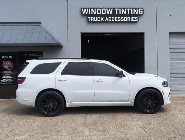 White SUV parked outside a window tinting and truck accessories shop.
