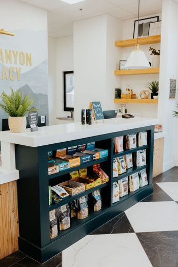 Checkout counter with snacks; teal cabinet, white countertop, wood shelves.