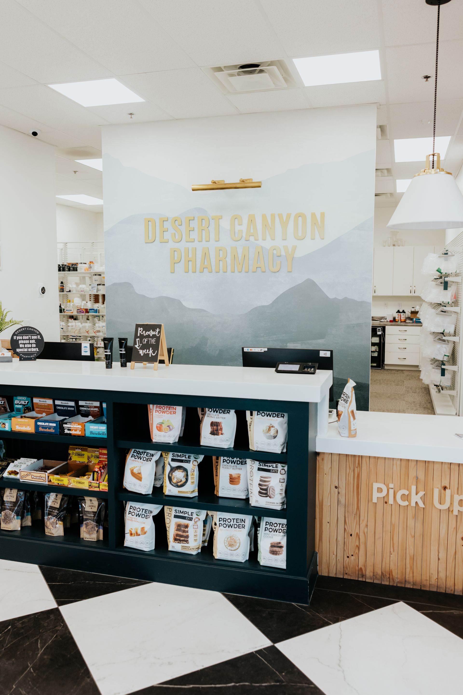 Interior of Desert Canyon Pharmacy with a mountain mural and counter.