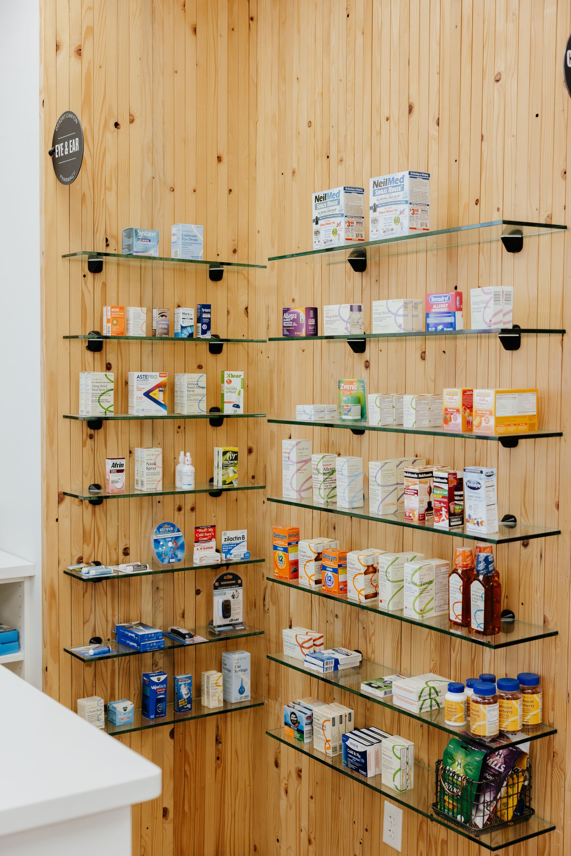 Shelves of medications and supplements on wooden wall in pharmacy.
