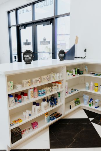 White interior shop with shelves of products on display; black and white tiled floor.