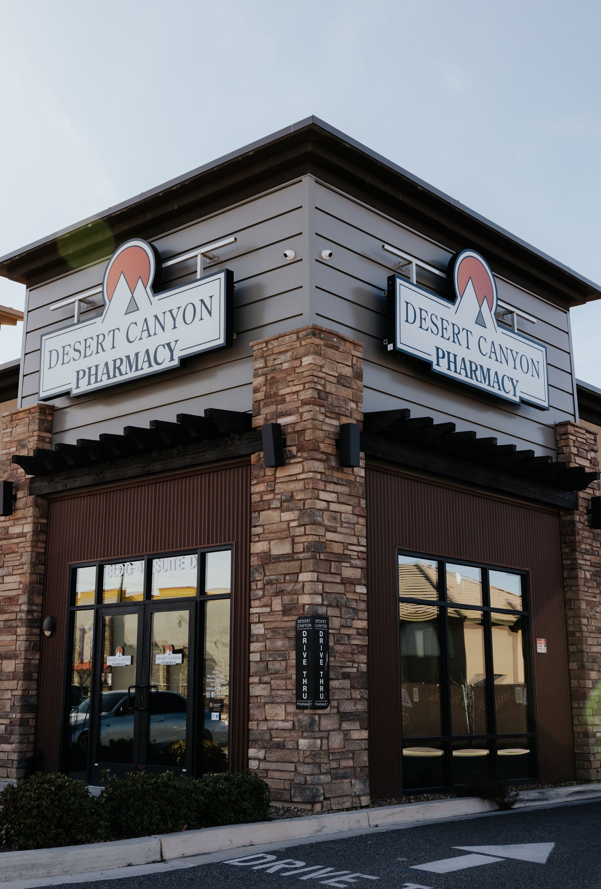Exterior of Desert Canyon Pharmacy building with brick and wood facade, large windows, and signage.