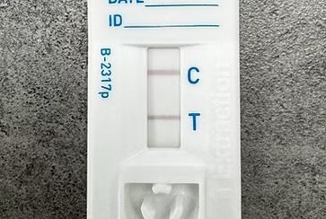 COVID-19 rapid test displaying a positive result; two lines present, one at 