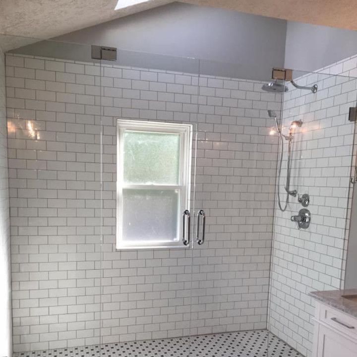 A bathroom with white brick walls and a walk in shower with a window.