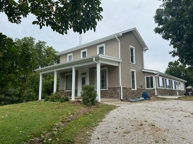 A large house with a porch and a gravel driveway