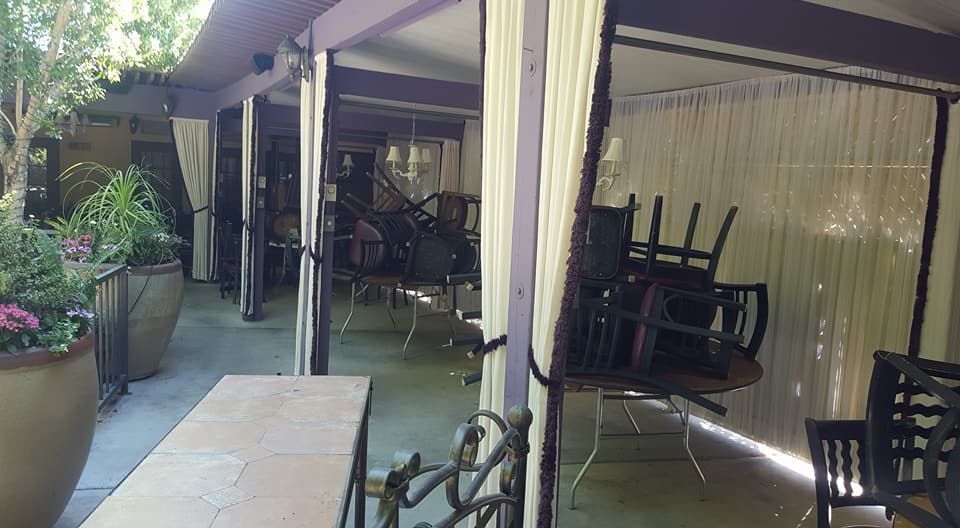 A patio with tables and chairs under a canopy.