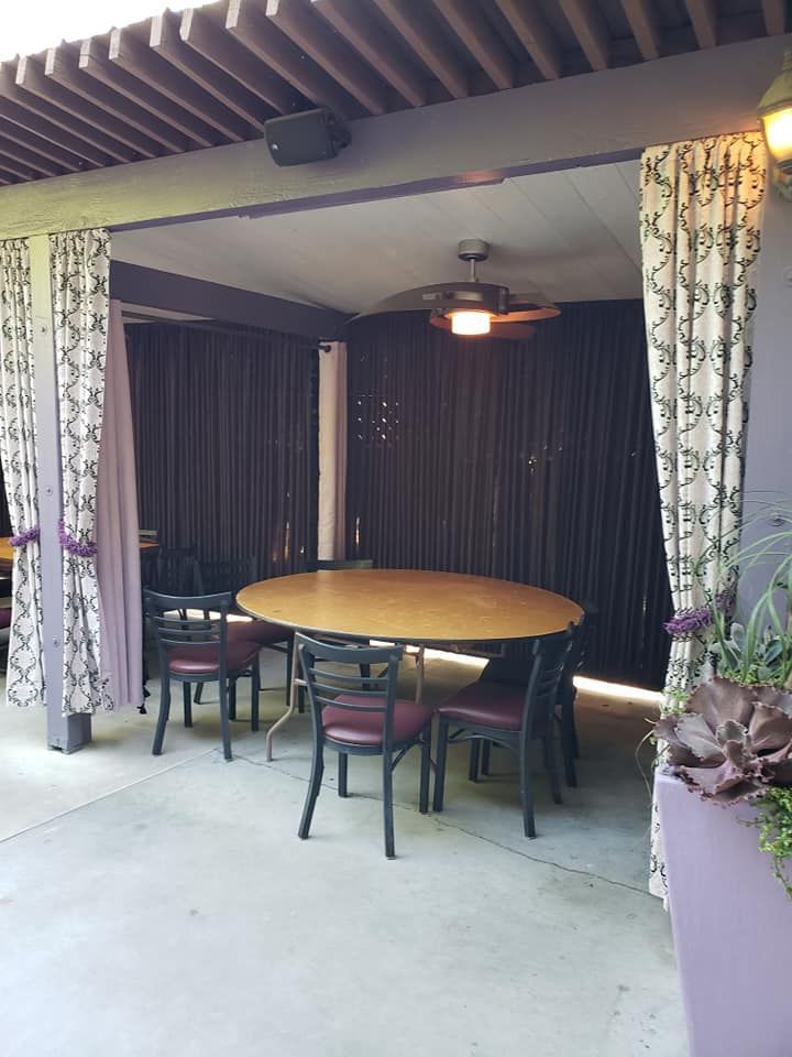 A patio with a table and chairs under a ceiling fan.