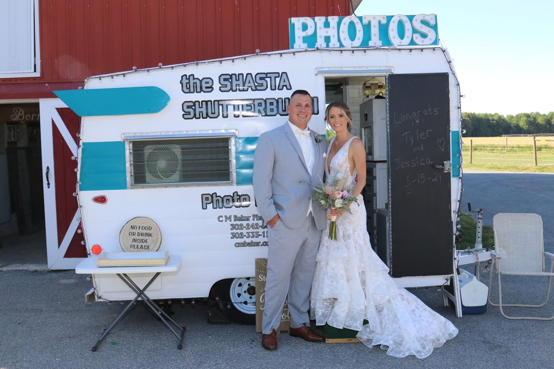 bride and groom smiling in front of vintage camper photo booth