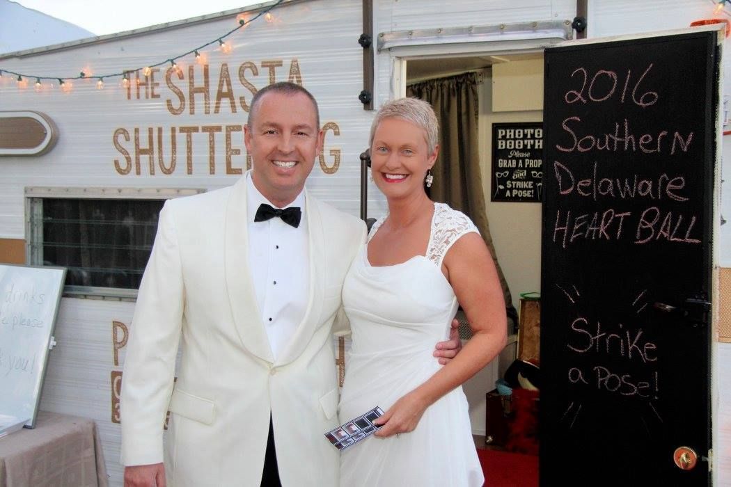 bride and groom smiling in front of vintage photo booth trailer