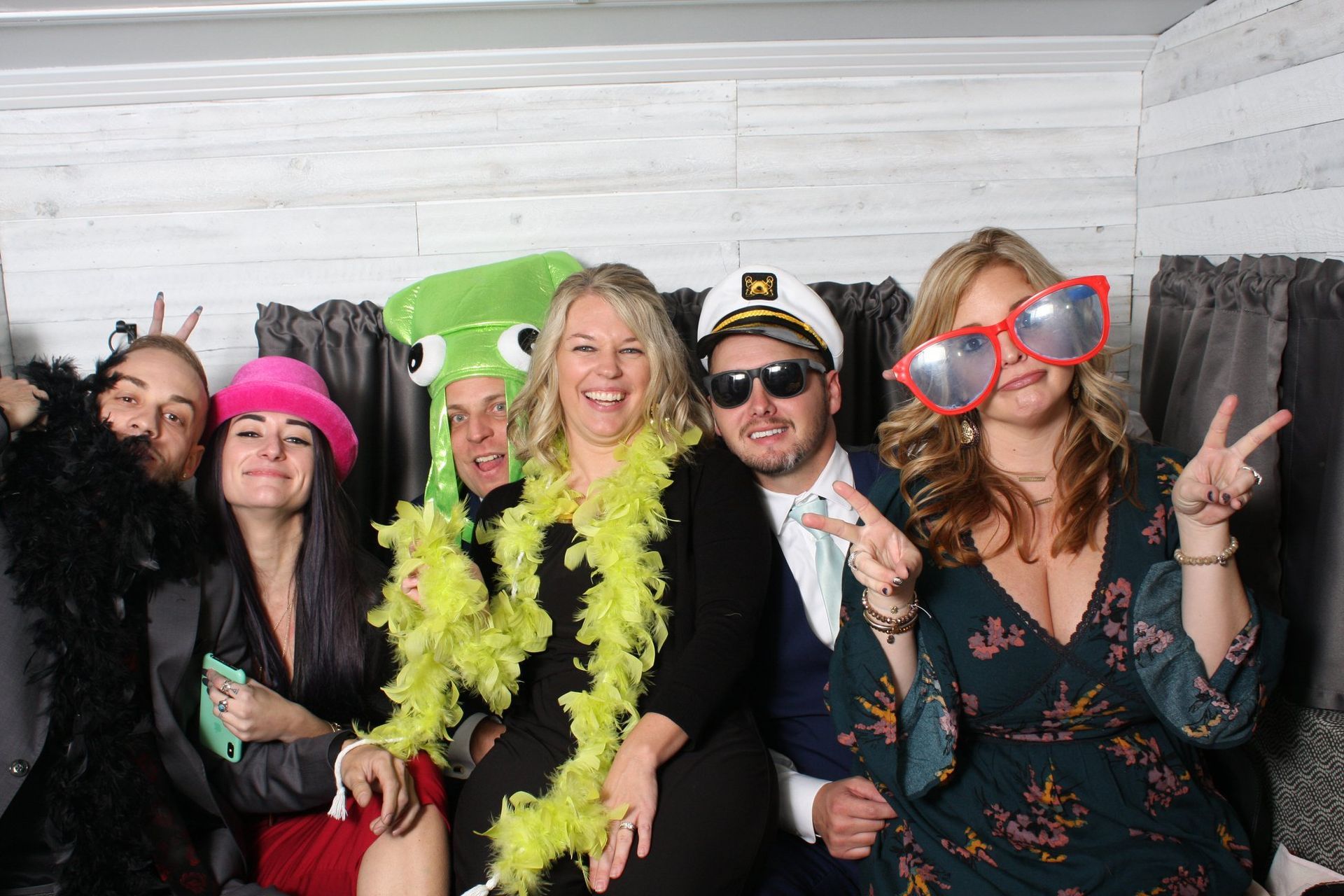 party guests smiling in photo booth with props