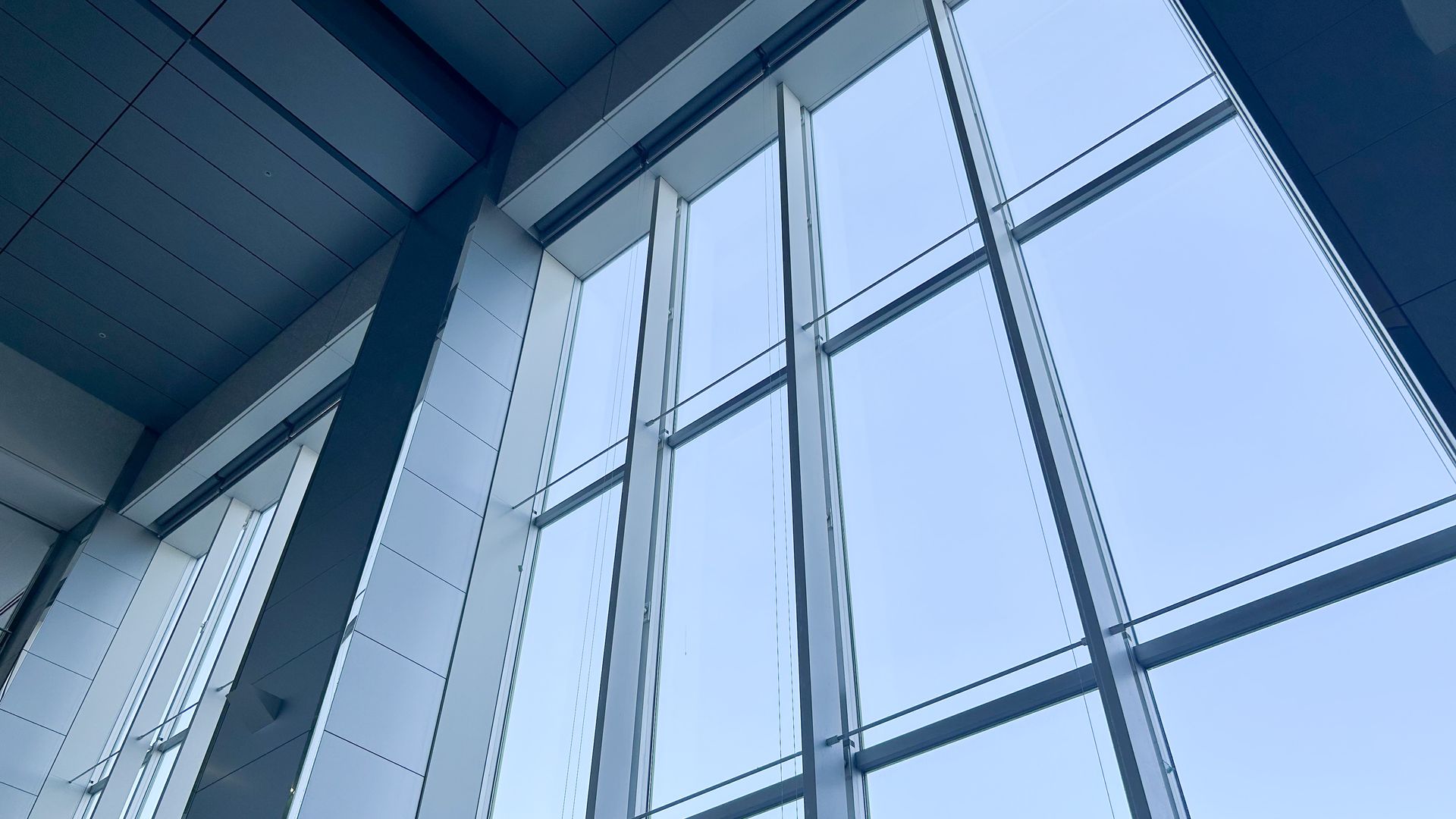 Vue bleutée de hautes fenêtres en verre et de poutres d'acier à l'intérieur d'un bâtiment moderne