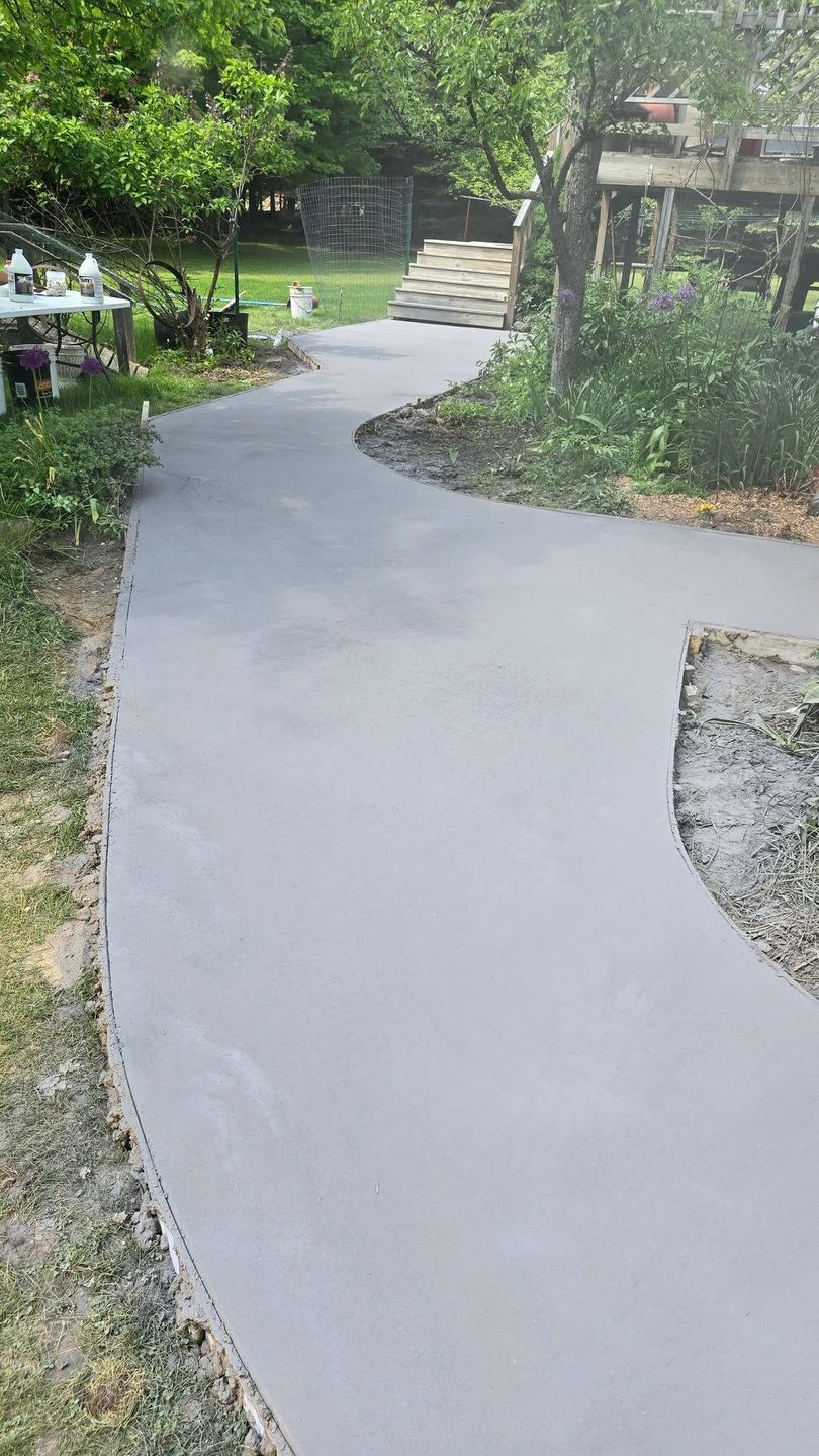 Curved light-gray garden path winding through lush greenery and stone steps ahead