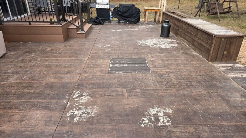 Weathered wooden deck with benches and a black trash can in a backyard patio area