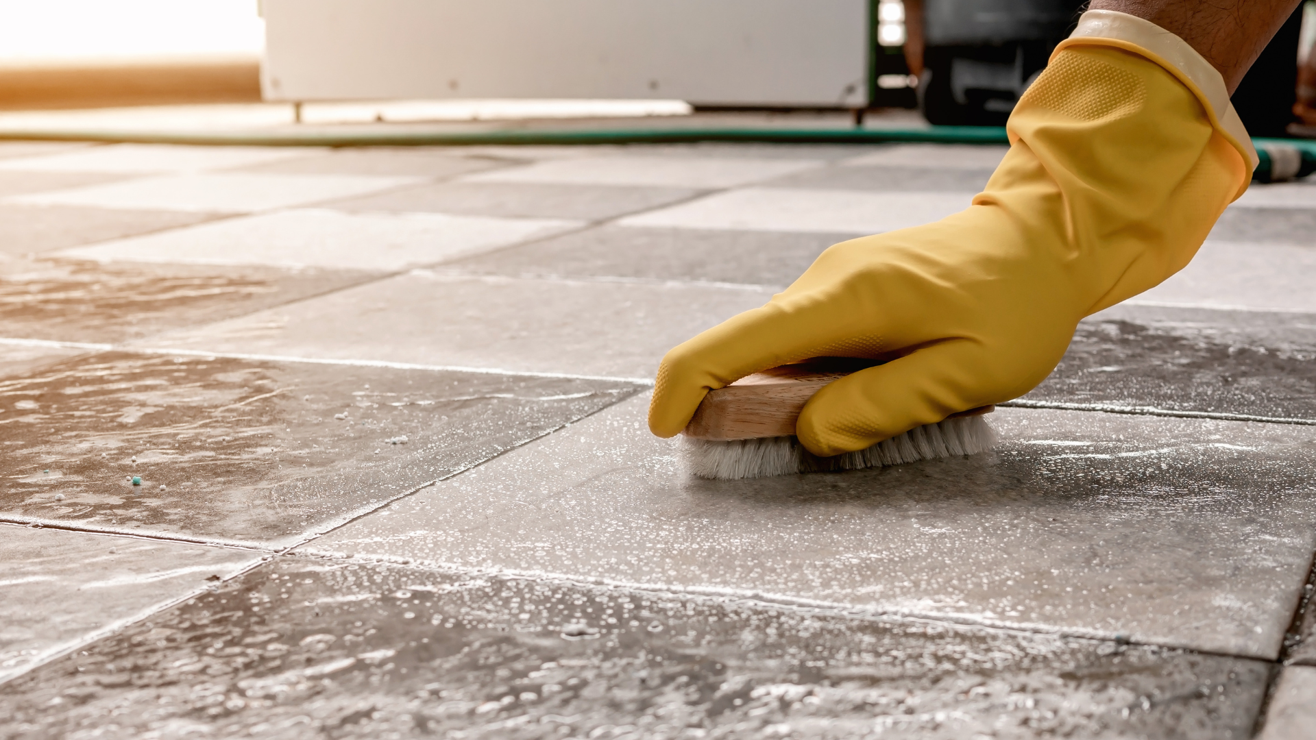 Yellow-gloved hand smoothing mortar between outdoor stone tiles